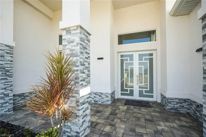 Property entrance featuring french doors, stucco siding, and stone siding