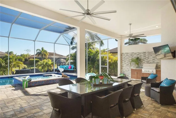 View of patio / terrace with a pool with connected hot tub, a lanai, a sunroom, ceiling fan, and an outdoor kitchen / dining area