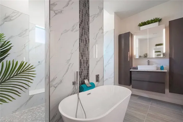 Bathroom with vanity, a marble finish shower, a freestanding bath, tile walls, and stone wall
