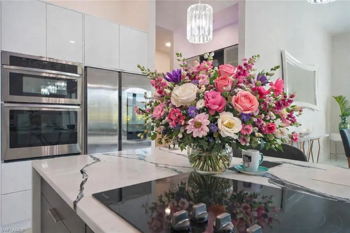 Kitchen featuring modern cabinets, stainless steel appliances, light stone countertops, and hanging lights