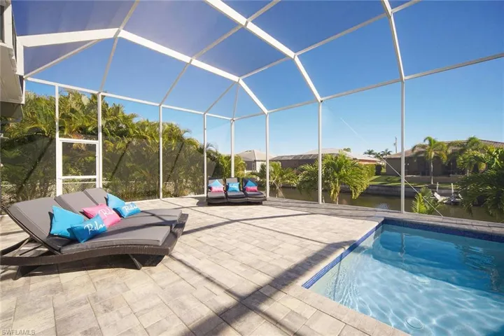 Swimming pool featuring a water view, glass enclosure, a sunroom, and a patio
