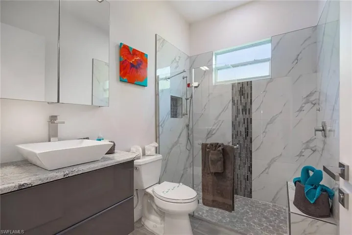 Bathroom featuring a marble finish shower and vanity