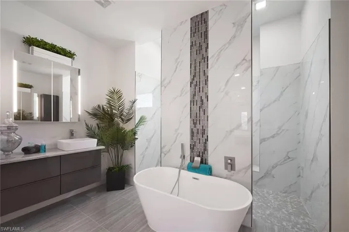 Bathroom featuring vanity, a marble finish shower, a soaking tub, tile walls, and stone wall