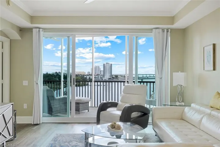 Living area featuring wood finished floors, plenty of natural light, ornamental molding, baseboards, and a water view
