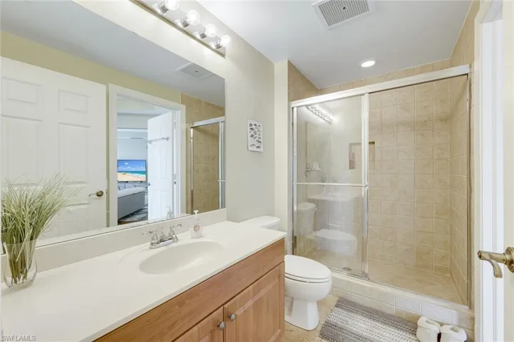 Ensuite bathroom with a shower stall, toilet, vanity, and tile patterned flooring