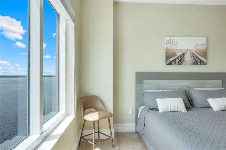 Tiled bedroom featuring multiple windows, a water view, and baseboards