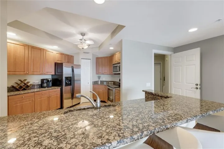 Kitchen with appliances with stainless steel finishes, a sink, a breakfast bar, recessed lighting, and ceiling fan
