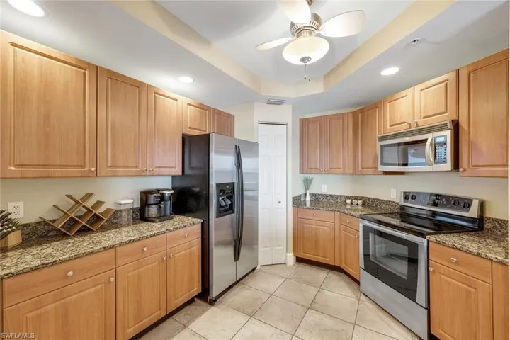 Kitchen featuring stainless steel appliances, recessed lighting, a tray ceiling, a ceiling fan, and light tile patterned floors