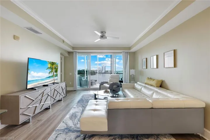 Living area featuring ceiling fan, wood finished floors, crown molding, and baseboards