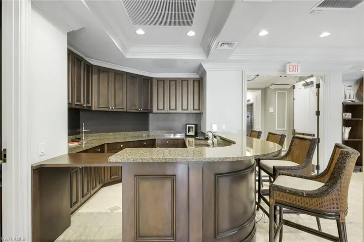 Kitchen featuring ornamental molding, a breakfast bar, light tile patterned floors, a sink, and a peninsula