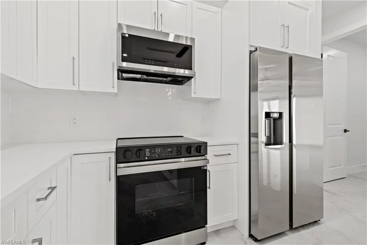 Kitchen with appliances with stainless steel finishes and white cabinetry