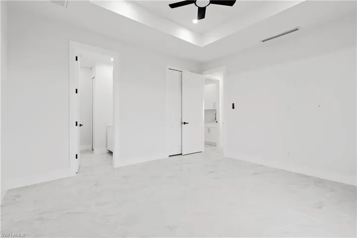 Unfurnished bedroom with a raised ceiling and ceiling fan