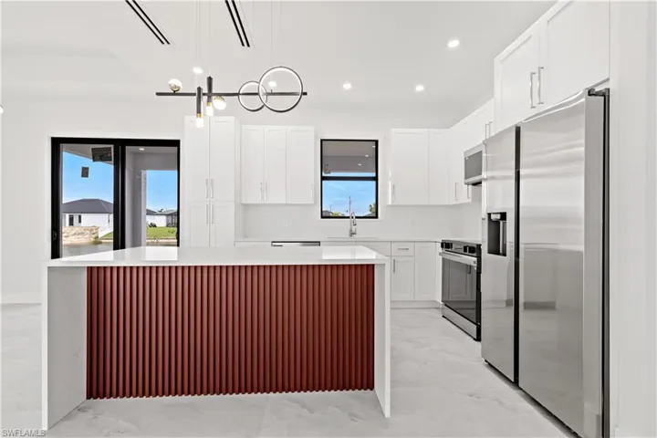 Kitchen featuring a kitchen island, white cabinetry, hanging light fixtures, and stainless steel appliances