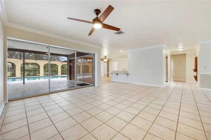 Empty room with crown molding, light tile patterned floors, and ceiling fan