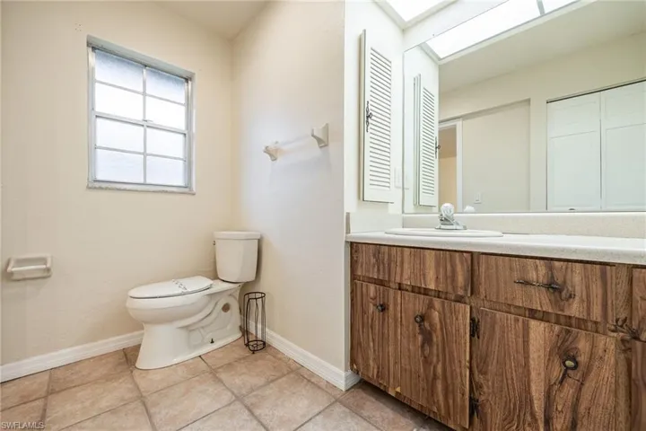 Bathroom with vanity, toilet, a skylight, and tile patterned flooring