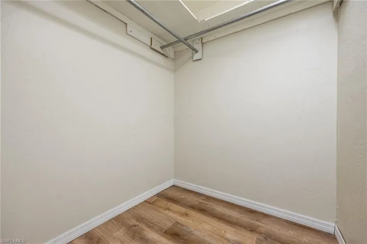 Walk in closet with hardwood / wood-style flooring