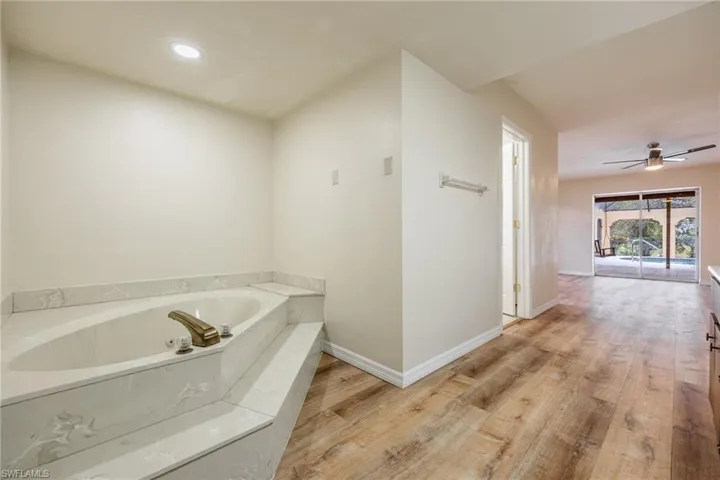Bathroom featuring a tub, hardwood / wood-style floors, and ceiling fan