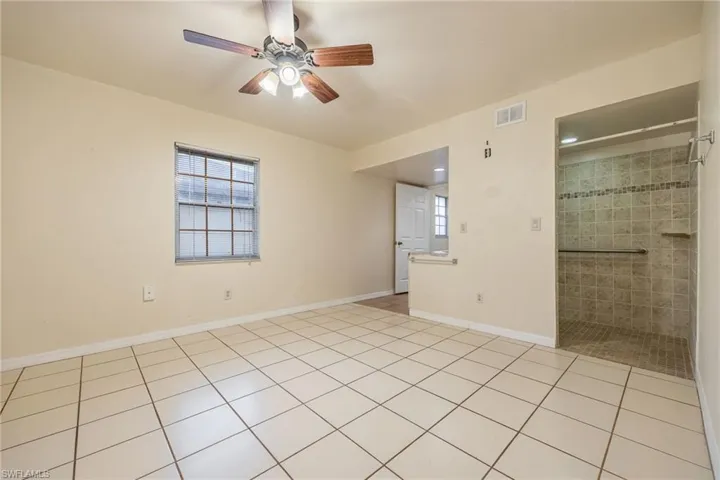 Tiled empty room with a healthy amount of sunlight and ceiling fan