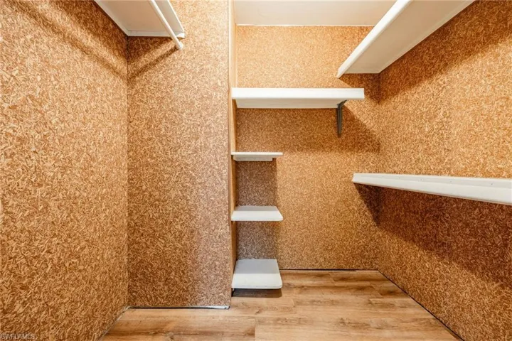 Walk in closet with hardwood / wood-style floors