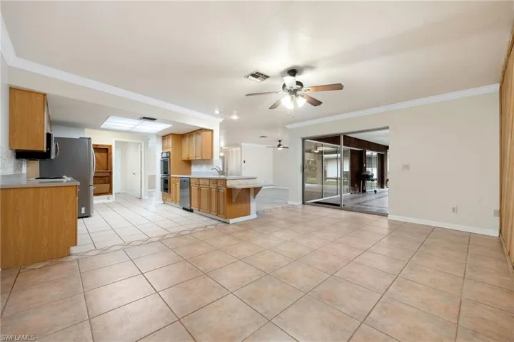 Kitchen with light tile patterned floors, appliances with stainless steel finishes, kitchen peninsula, ceiling fan, and backsplash