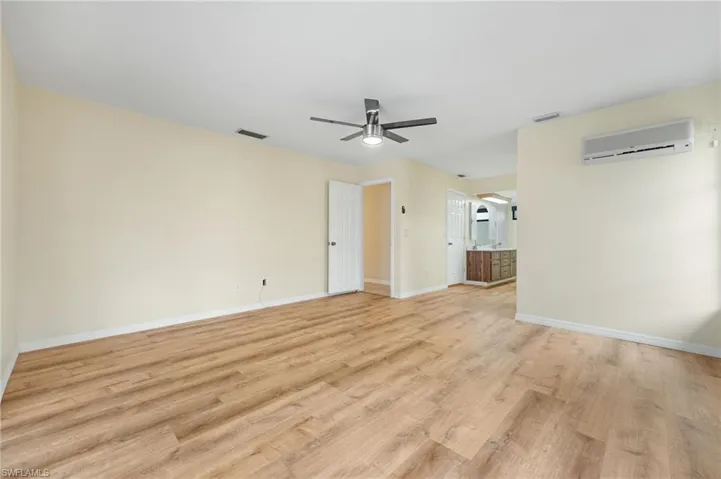 Unfurnished room with ceiling fan, a wall mounted air conditioner, and light hardwood / wood-style floors