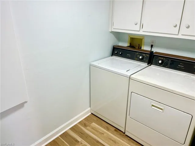 Laundry room featuring independent washer and dryer, cabinets, and light hardwood / wood-style flooring
