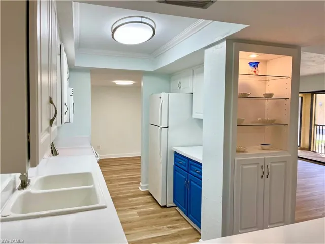 Kitchen with blue cabinets, sink, white cabinets, and light hardwood / wood-style flooring