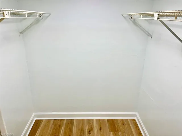 Walk in closet with wood-type flooring