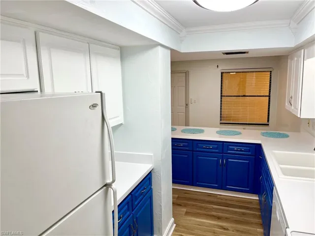 Kitchen featuring sink, blue cabinets, white cabinetry, light hardwood / wood-style flooring, and white refrigerator