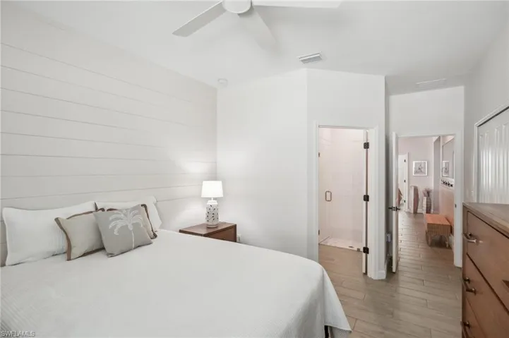 Bedroom featuring visible vents, light wood-type flooring, ensuite bathroom, and a ceiling fan