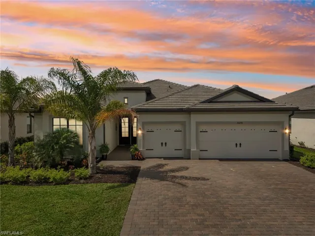View of front of house featuring a tiled roof, decorative driveway, an attached garage, and stucco siding
