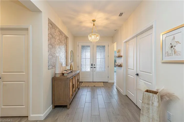 Entryway featuring baseboards, a chandelier, french doors, visible vents, and light wood finished floors