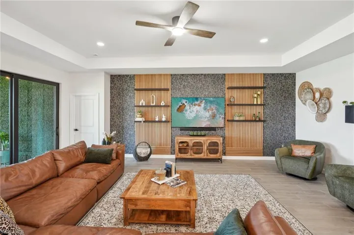Living area featuring an accent wall, wood finished floors, a ceiling fan, and recessed lighting