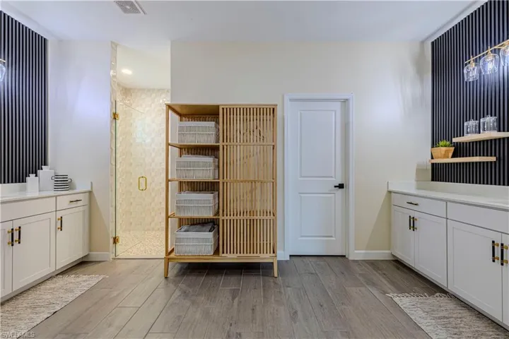 Bathroom with vanity, baseboards, a shower stall, visible vents, and wood finished floors