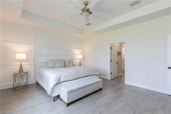 Bedroom with light wood-style floors, a decorative wall, baseboards, and visible vents