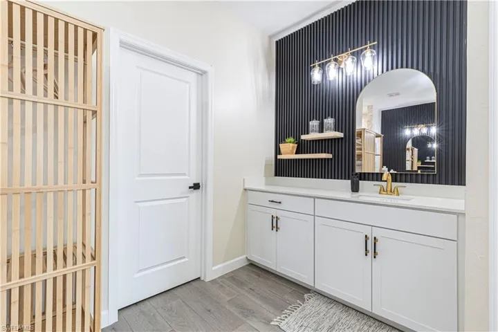 Bathroom featuring vanity, baseboards, and wood finished floors