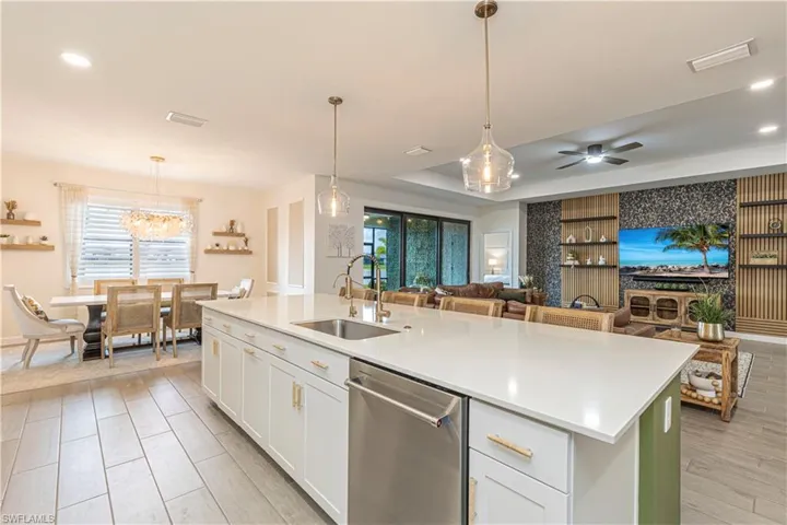 Kitchen featuring plenty of natural light, light countertops, a kitchen island with sink, dishwasher, and a sink