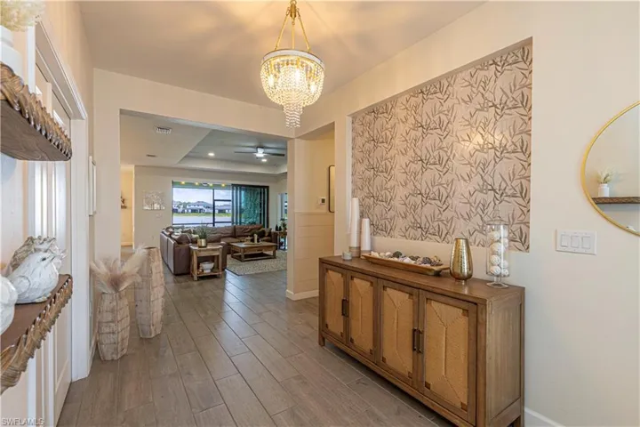 Hall with visible vents, an inviting chandelier, and wood finished floors