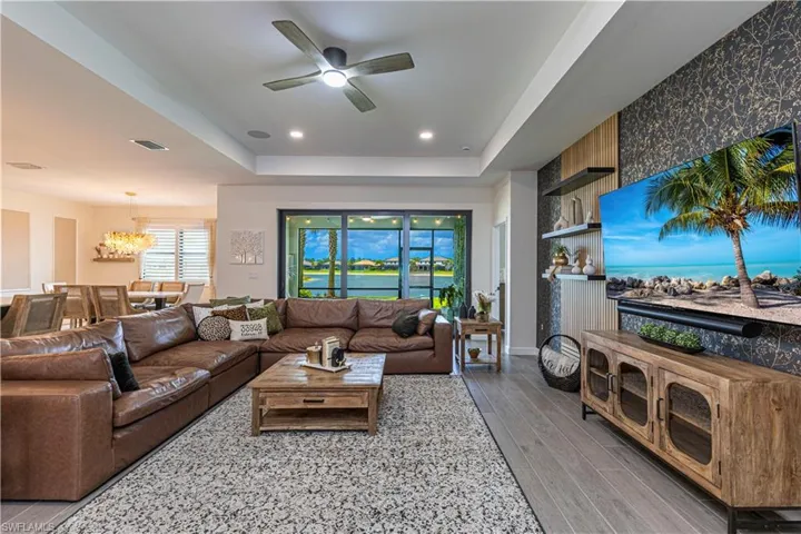 Living room with visible vents, a tray ceiling, recessed lighting, wood finished floors, and ceiling fan with notable chandelier
