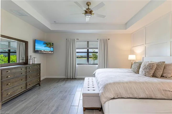 Bedroom featuring visible vents, a tray ceiling, baseboards, and wood finished floors