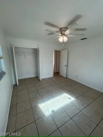 Unfurnished bedroom with light tile patterned floors, a ceiling fan, and a closet