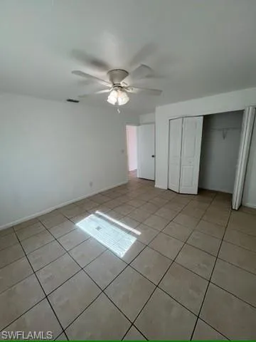 Unfurnished bedroom with a closet, light tile patterned floors, and ceiling fan