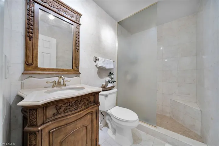 Bathroom with tile walls, vanity, a walk in shower, and tile patterned floors
