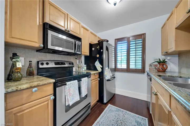Kitchen with stainless steel appliances, light stone counters, decorative backsplash, and light wood finish cabinets