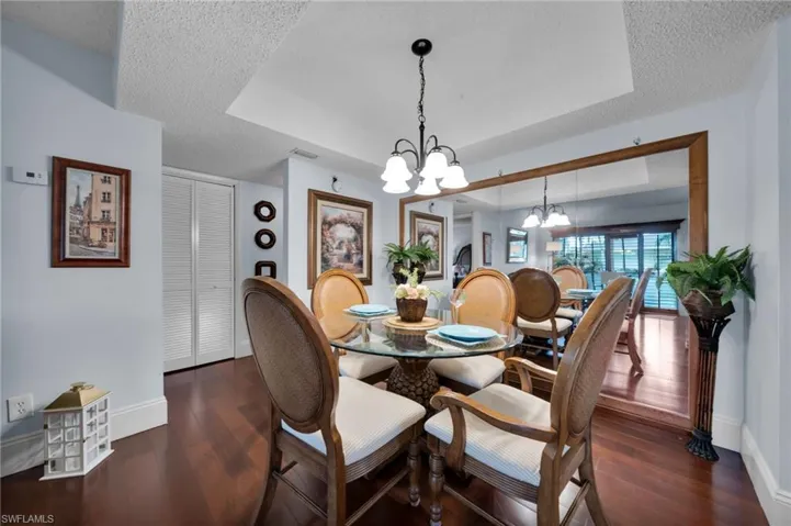 Dining area featuring a chandelier, a tray ceiling, a textured ceiling, and dark wood-type flooring