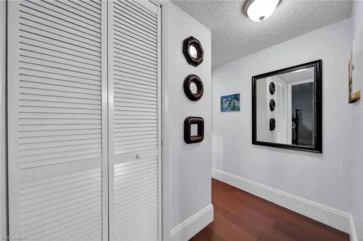 Hall featuring a textured ceiling and dark wood-style flooring