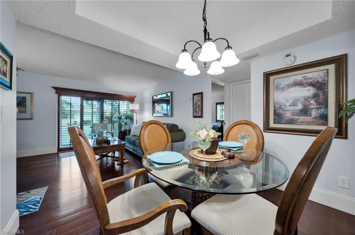 Dining room with suspended lighting, hardwood / wood-style floors, and a textured ceiling