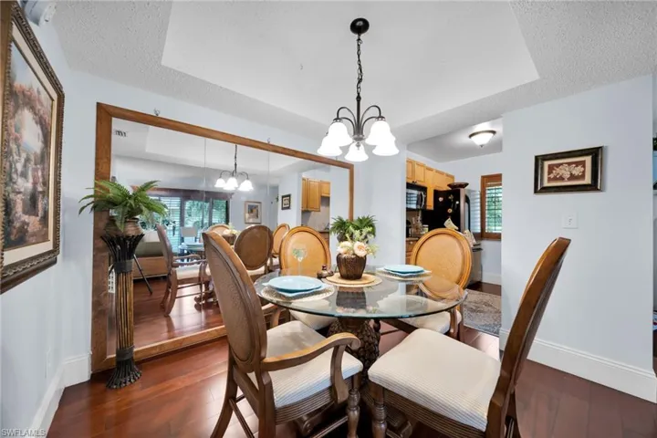 Dining room featuring a chandelier, a textured ceiling, dark wood-style flooring, and a tray ceiling