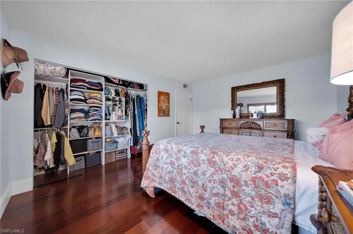 Bedroom with dark wood-style floors, a closet, and a textured ceiling