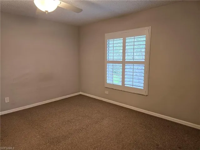 2nd bedroom featuring a textured ceiling, colored carpet, and a ceiling fan